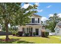 Two-story house with inviting front porch, lush lawn, mature tree, and private driveway at 8987 Planters Row Ln, Summerville, SC 29485