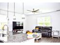 Open-concept living area featuring a large sofa, modern ceiling fan, and hardwood floors at 9694 Roseberry St, Ladson, SC 29456