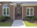 Inviting brick home entrance with arched window, decorative plants, and a solid wood door at 1280 Waterfront Dr, Mount Pleasant, SC 29464