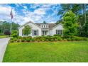 Beautiful home featuring a lush green lawn, manicured shrubs, and mature trees, exuding curb appeal at 225 Camber Rd, Huger, SC 29450