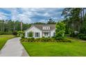 Charming home with a well-manicured lawn, mature trees, and a welcoming driveway, complete with an American flag at 225 Camber Rd, Huger, SC 29450