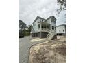 Two-story home with pale siding, elevated on pilings with gravel driveway at 2790 Burden Creek Rd, Johns Island, SC 29455