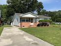 View of home with concrete driveway, manicured lawn, tidy landscaping, and brick foundation at 105 Pandora Dr, Goose Creek, SC 29445