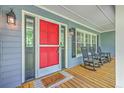 Charming porch with a bright red front door and inviting rocking chairs and views at 121 Woodland Dr, Summerville, SC 29485
