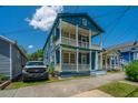 Charming two-story blue home with a white porch on a sunny day, perfect for enjoying the outdoors at 200 Fishburne St, Charleston, SC 29403