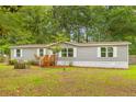 Single-story home with gray siding, white trim, wood porch and stairs surrounded by a beautiful lawn and wooded area at 201 Frank St, Summerville, SC 29483