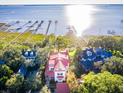 Aerial view showcases a beautiful white multi-story home with a red roof, surrounded by lush trees and long docks at 202 Bank St, Mount Pleasant, SC 29464