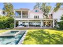 Backyard of a home with a covered porch, a pool, and a brick fireplace surrounded by a green yard at 202 Bank St, Mount Pleasant, SC 29464