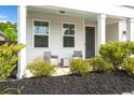 Cozy front porch features charming seating, complemented by fresh landscaping and a welcoming entryway at 203 Yeamans Way, Summerville, SC 29483