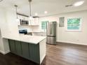 Well-lit kitchen featuring stainless steel appliances, white cabinets, and a stylish green island at 208 Orange St, Walterboro, SC 29488