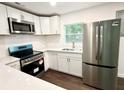 Close-up shot of kitchen with stainless steel appliances and stylish white cabinetry and quartz counters at 208 Orange St, Walterboro, SC 29488