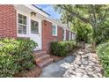 Side view of a brick home with well-maintained landscaping and a charming wooden gate leading to the backyard at 31 Lyttleton Ave, Charleston, SC 29407