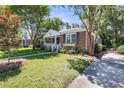 A charming house with a brick facade and a well-manicured lawn, complemented by mature trees and foliage at 31 Lyttleton Ave, Charleston, SC 29407