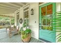 Cozy front porch with wicker chairs, a vibrant plant, and a stylish aqua-colored door at 312 Hobcaw Dr, Mount Pleasant, SC 29464