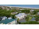 Stunning aerial view showcasing a white beach house with palm trees, ocean, and neighboring colorful homes at 4001 Palm Blvd, Isle of Palms, SC 29451