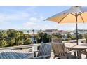 Relax on the deck with seating, enjoying ocean views and palm trees under a sunny sky with a white umbrella at 4001 Palm Blvd, Isle of Palms, SC 29451