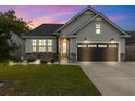 Charming single-Gathering home with warm exterior lights, stone accents, and a beautifully illuminated lawn at dusk at 404 Omaha Dr, Moncks Corner, SC 29461