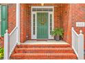 Inviting brick front porch featuring a green door adorned with a wreath and white railing on the steps at 416 Prestwick Ct, Summerville, SC 29483