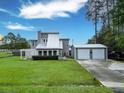 View of a two-story home with a metal roof, a detached two-car garage, and a spacious lawn at 49 Auld Brass Rd, Walterboro, SC 29488
