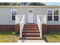 Close-up of home's entrance featuring brick steps, white railing, and a decorative front door with the house number 513 at 513 Pauline Dr, Bonneau, SC 29431