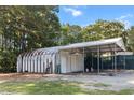 View of a functional metal outbuilding with two garage doors, side door, and a covered parking area at 513 Pauline Dr, Bonneau, SC 29431