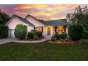 Charming single-story home with manicured landscaping, white siding and a dramatic sunset at 1077 Farmington Rd, Charleston, SC 29412
