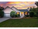 Charming single-story home with manicured landscaping, white siding and a dramatic sunset backdrop at 1077 Farmington Rd, Charleston, SC 29412