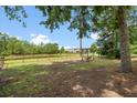 Expansive backyard featuring a tranquil pond, wooden fence, mature trees, and a charming swing set at 1578 Stanwick Dr, Johns Island, SC 29455