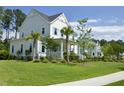 Inviting two-story home showcasing a lush lawn, mature trees, and a quaint covered front porch with blue shutters at 1723 Bolden Dr, Mount Pleasant, SC 29466