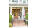 Charming front entrance with wooden door, brick steps, American flag and seasonal decorations at 4215 Ten Shillings Way, Ravenel, SC 29470