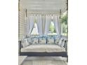 Inviting porch swing with white cushions and floral pillows, perfect for relaxing outdoors at 482 Planters Trace Dr, Charleston, SC 29412