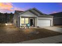 Charming home with beige siding and a two-car garage, featuring a welcoming front porch at twilight at 576 Polaris Way, Summerville, SC 29486