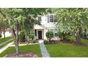 Inviting two-story home with a well-maintained lawn, beautiful trees, and a paved walkway to the front door at 8967 N Red Maple Cir, Summerville, SC 29485