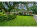 Beautifully landscaped front yard of a brick home, featuring mature trees and green grass at 930 Stiles Dr, Charleston, SC 29412