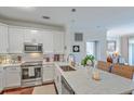 Bright kitchen features white cabinets, stainless steel appliances, and an island with marble countertop and wicker barstools at 21 George St # 203, Charleston, SC 29401