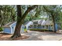 Inviting blue home features a well-maintained lawn, mature trees, and an attached garage with a paved driveway at 2653 Seabrook Island Rd, Seabrook Island, SC 29455