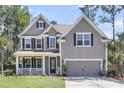 Inviting two-story home with a cozy front porch, black shutters, and beautiful lawn at 404 Bowstring Dr, Huger, SC 29450