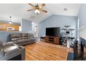 Spacious living room with wood floors, vaulted ceiling, fireplace, and a large TV perfect for entertaining at 432 Equinox Cir, Ladson, SC 29456