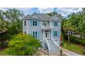 Two-story home featuring light grey siding, blue shutters, front yard with trees and manicured landscaping at 5847 Back Bay Dr, Isle of Palms, SC 29451