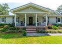 Welcoming front porch with classic columns, brick steps, and cozy seating amidst colorful landscaping at 806 Appii Rd, Moncks Corner, SC 29461