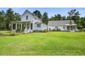 Beautiful two-story white farmhouse with a welcoming porch and a lush green lawn at 105 Bobcat Ln, Ravenel, SC 29470