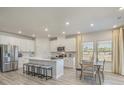 Bright open-concept kitchen and dining area with stainless steel appliances, white cabinets, and an island with seating at 109 Indigo Cove Blvd, Summerville, SC 29486