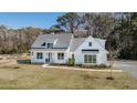 Beautifully landscaped two-story home with a classic white exterior, dark roof, and cozy front porch at 1174 Hitchfield Ln, Awendaw, SC 29429