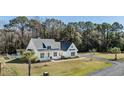 Inviting two-story home with a classic white exterior, dark roof, well-manicured lawn and driveway at 1174 Hitchfield Ln, Awendaw, SC 29429