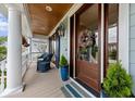 Inviting front porch with rocking chairs, stylish decor, wood ceiling, and a beautiful front door at 1597 Rivertowne Country Club Dr, Mount Pleasant, SC 29466