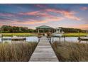 Picturesque dock with a covered seating area extending into a tranquil marsh at sunset at 1635 Bull Creek Ln, Charleston, SC 29414