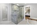 Modern bathroom with glass shower, soaking tub, gray tile, and a view of the bedroom at 1673 Mcclain St, Charleston, SC 29407