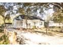 A quaint white home with a lovely arched porch, surrounded by lush greenery and a long driveway at 203 Weiters St, Walterboro, SC 29488
