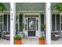 Inviting front porch with potted plants, comfortable seating, and a stylish entrance door at 216 Foxbank Plantation Blvd, Moncks Corner, SC 29461