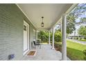 Inviting front porch with classic columns, seating, and stylish lighting fixture at 217 Quaker Rd, Saint George, SC 29477